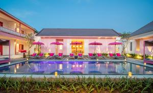 a pool with chairs and umbrellas in front of a house at PinkPrivate Balangan - for Cool Adults Only in Jimbaran