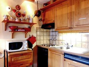 a kitchen with wooden cabinets and a sink and a microwave at Cosy Apartment in Bellwald 68 m² Mountain View in Bellwald