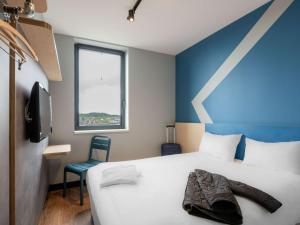 - une chambre avec un lit blanc et un mur bleu dans l'établissement ibis budget Leuven Centrum, à Louvain