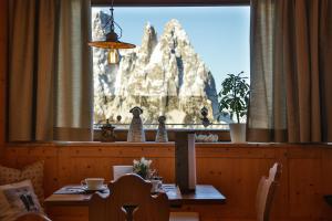 un comedor con una mesa frente a una ventana en Berghotel Zorzi, en Alpe di Siusi