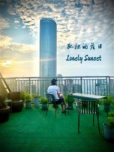 a man sitting at a table on a balcony at 弱水咖啡国际青旅Only Cafe and Backpacker in Chongqing