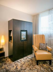 a hotel room with a chair and a cabinet at ARCOTEL Camino Stuttgart in Stuttgart