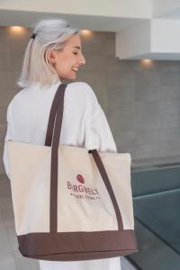 a woman holding a tote bag in a kitchen at Hotel Bergwelt in Längenfeld