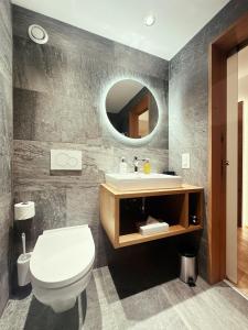 a bathroom with a toilet and a sink and a mirror at Hotel Panorama in Hasliberg