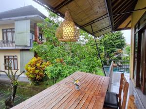 un tavolo in legno con lampadario pendente su un patio di Nyoman Sandi Guest House ad Ubud