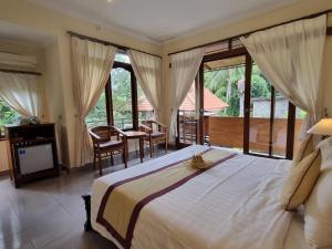 una camera con un grande letto e un balcone di Nyoman Sandi Guest House ad Ubud