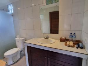 bagno con lavandino, servizi igienici e specchio di Nyoman Sandi Guest House ad Ubud