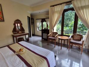 una camera con letto e alcune sedie e finestre di Nyoman Sandi Guest House ad Ubud