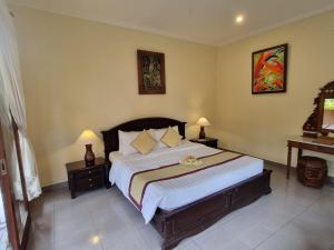 una camera da letto con un grande letto con due tavoli e due lampade di Nyoman Sandi Guest House ad Ubud