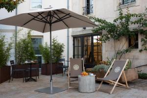 - une terrasse avec 2 chaises et un parasol dans l'établissement Le Saint-Nicolas, à La Rochelle