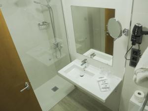 y baño blanco con lavabo y ducha. en Hotel Verol, en Las Palmas de Gran Canaria