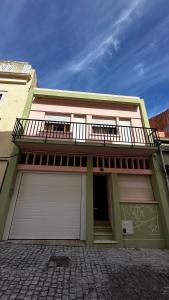 een huis met twee garagedeuren en een balkon bij Pátio Privado com Churrasqueira by Férias em Figueira in Figueira da Foz