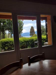 uma sala de jantar com vista para o oceano através das janelas em Melewe em Villa La Angostura