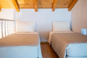 two beds in a small room with wooden ceilings at Aktaion Resort in Gythio