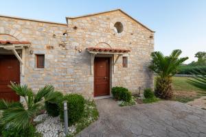 a stone house with a brown door and a yard at Aktaion Resort in Gythio