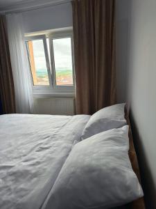 a white bed in a room with a window at B7 Apartament in Ocna-Mureşului