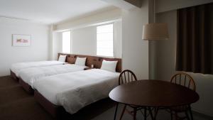 a hotel room with two beds and a table at Shin-Osaka Station Hotel in Osaka