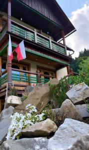 ein Gebäude mit Flaggen und Felsen davor in der Unterkunft Gościniec Karpacka Dusza in Szczawnica