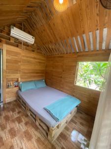 Mèo Home - Bụi Homestay في Dien Khanh: سرير في غرفة خشبية مع نافذة