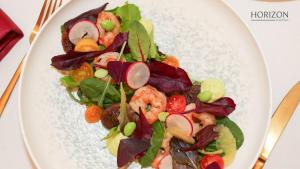 a white plate with a salad with shrimp and vegetables at Hotel Aro Palace in Braşov