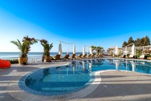 a swimming pool with chairs and the ocean in the background at Perla Apartments First Line in Nesebar