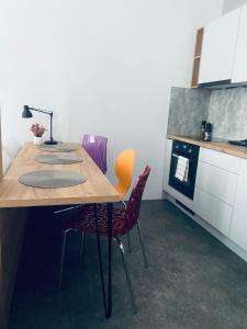 uma cozinha com uma mesa de madeira e cadeiras roxas em Apartment Center Zilina near Train and Bus station em Žilina