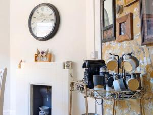 une horloge sur un mur au-dessus d'une cheminée avec des casseroles et des poêles dans l'établissement Church Path, à Emsworth