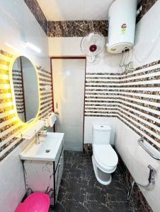 een badkamer met een toilet, een wastafel en een spiegel bij Divya Anubhuti Pravas in New Delhi