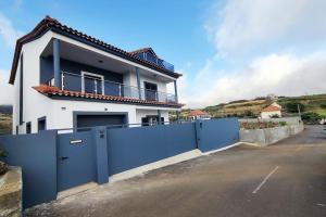 a white house with a blue fence in front of it at Casa Neto Jardim in Calheta