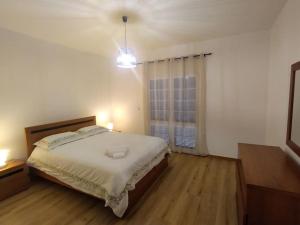 a white bedroom with a bed and a window at Casa Neto Jardim in Calheta