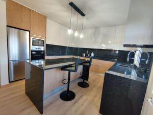 a kitchen with a counter and a bar with a stool at Casa Neto Jardim in Calheta