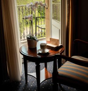 un tavolo con una tazza di caffè e un fiore sopra di Grand Hotel et Centre Thermal d'Yverdon-les-Bains a Yverdon-les-Bains