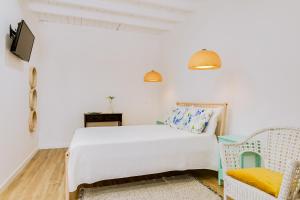 a white bedroom with a bed and a chair at Quinta Almargem Lusitano - Farm House in Tavira