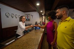 Hotel Dan Inn São José do Rio Preto في ساو جوزيه دو ريو بريتو: امرأة تقف عند بار مع زبون