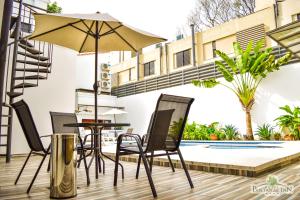 een patio met een tafel en stoelen en een parasol bij SBS Hotel & Spa in Asuncion