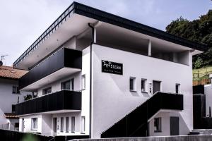 a white building with a black sign on it at Apartmenthouse STERN in Vipiteno