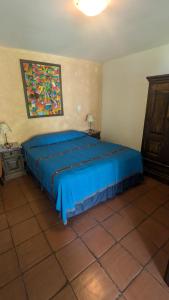 a bedroom with a blue bed and a painting on the wall at Casa Elena in Antigua Guatemala