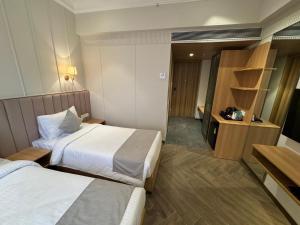 Hotel Mumbai House Mindspace Malad في مومباي: غرفه فندقيه سريرين وتلفزيون