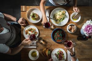 un grupo de personas sentadas alrededor de una mesa con platos de comida en Hotel Admiral Lugano, en Lugano