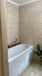 a white tub in a bathroom with a tiled wall at Tudor Apartament in Ocna-Mureşului