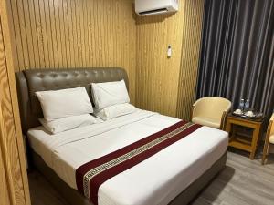 um quarto com uma cama grande e lençóis brancos em SS Hotel Seremban em Seremban