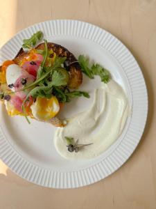 um prato branco com uma sanduíche com salada e molho em Auberge du Jardin em Petit-Saguenay