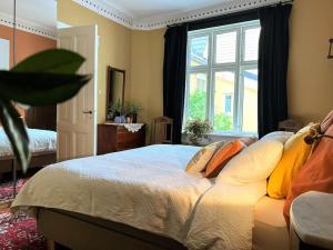 um quarto com uma cama com almofadas e uma janela em Spacious historical art oasis in the city center em Bergen