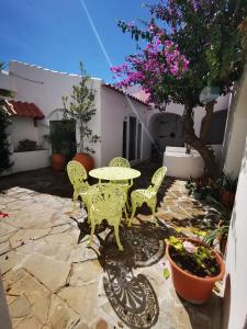 eine Terrasse mit einem Tisch, Stühlen und einem Baum in der Unterkunft Castle House and Beach in Sines