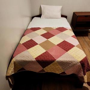 een bed met een kleurrijke quilt erop bij Hostal Johumaji in Chachapoyas