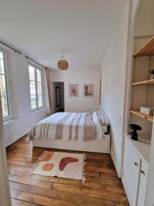 - une chambre blanche avec un lit et du parquet dans l'établissement Magnifique Appartement - Driant, à Troyes