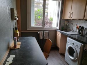 a kitchen with a table and a washing machine at Chambre 1 lit double in Strasbourg