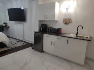 cocina con armarios blancos, fregadero y encimera en Troon Harmony - Room 1, en Durban