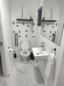 Baño blanco con aseo y lavamanos en Troon Harmony - Room 1, en Durban