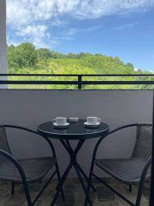 - une table avec deux chaises et deux tasses sur le balcon dans l'établissement APARTMENT 7 -Free Garage- SARAJEVO -Dobrinja- -Ilidza- -Center-, à Sarajevo